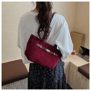 Deep burgundy tote bag in frosted leather finish shown on a model in a cozy indoor setting