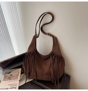 Detail of dark brown suede hobo bag with long side tassels and adjustable metal buckle