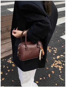 Brown bowling bag with lychee texture and wooden beads on an autumn bench