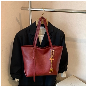 Dettaglio della borsa tote in ecopelle marrone con nappa di perle in legno etnico
