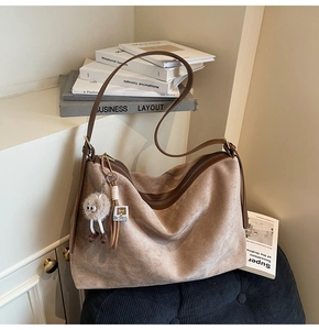 Détail d'un sac cabas en simili daim marron avec pendentif en peluche et fermeture éclair