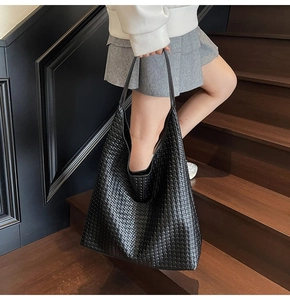 Detail view of a large black woven tote bag made of high-quality faux leather material