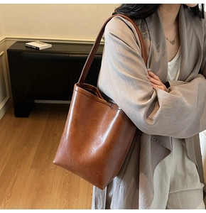 Close-up of caramel brown leather bucket bag with smooth glossy finish and long shoulder strap