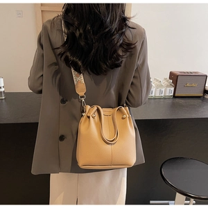 Détail du sac seau camel en cuir grainé avec bandoulière jacquard géométrique