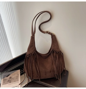Close-up of vintage dark brown suede hobo bag with long fringes and gold buckle