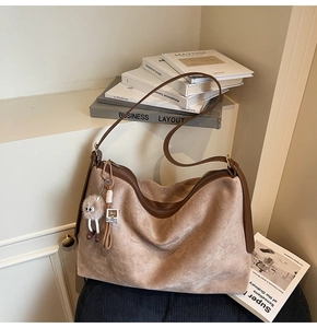Détail du sac cabas en daim camel avec bordure en cuir marron et breloque en peluche