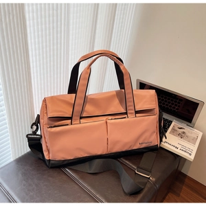 Sac de sport rose avec compartiment humide posé sur un fauteuil avec accessoires de voyage