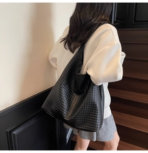 Detail shot of a black woven tote bag showing the soft texture and hobo style on a model