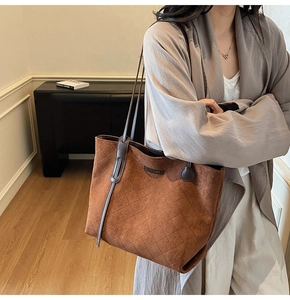 Detailed side view of brown suede tote bag with quilted pattern and slim shoulder strap