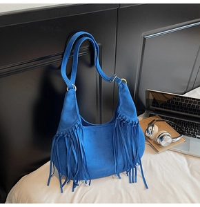 Detail view of Klein blue suede hobo bag with long fringes and metal strap buckles