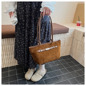 Detailed view of a brown suede tote bag with leather straps and metal buckle accent