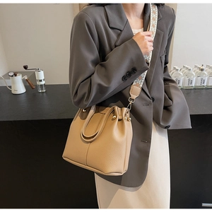 Détail du sac seau beige avec bandoulière ethnique tissée et finitions en métal