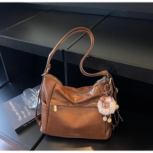 Close-up of vintage brown tote bag with leather texture and white plush sheep charm