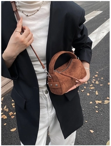 Braune gefrostete Wildleder-Handtasche mit runden Griffen und Nieten in herbstlicher Szene