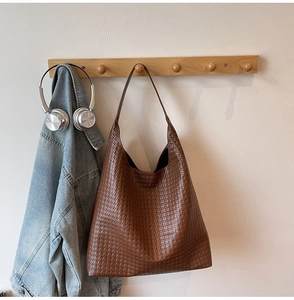 Detailed view of brown woven texture on hobo tote bag hanging on wooden rack