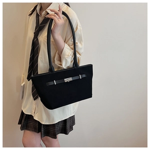 Detail of a black matte tote bag with metal buckle on a preppy style outfit