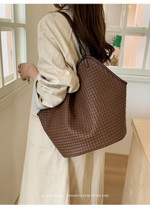 Close-up of brown woven bucket bag featuring detailed texture and long shoulder strap
