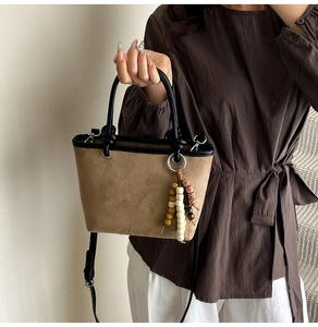 Detail of leopard print bucket bag with ethnic wooden bead charm and crossbody strap