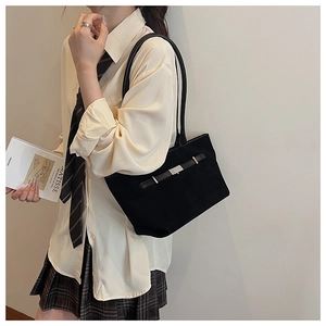 Close-up of black suede bucket bag featuring silver buckle detail and slim shoulder straps