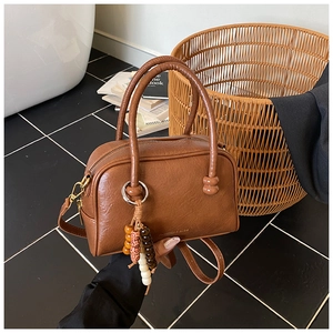 Détail du sac à main carré en cuir marron avec breloque ethnique et fermoirs dorés