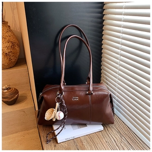 Detail view of vintage dark brown faux leather Boston bag with baseball charm accessories