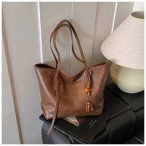 Dettaglio di una borsa tote vintage marrone con trama in pelle e nappa di perle di legno