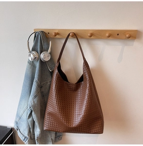 Detail of deep brown tote bag with premium woven texture hanging in a lifestyle scene