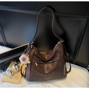 Detailed close-up of a dark brown Hobo bag with plush sheep charm and zipper pocket