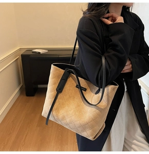 Detail of khaki suede tote bag featuring diamond quilting and black shoulder strap