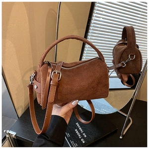 Detailansicht der dunkelbraunen Wildleder-Zylindertasche mit Retro-Schnalle und Schultergurt