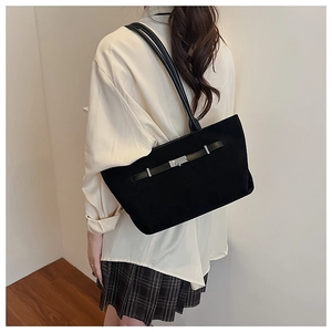Side view of a large black suede tote bag with silver buckle worn by a female model