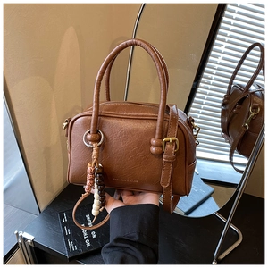 Detail of a brown Boston bowling bag with lychee texture and wooden bead tassel