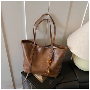 Dettaglio borsa shopper vintage marrone con elegante nappa di perline e tracolla