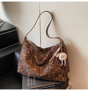 Détail du sac hobo en daim à imprimé léopard avec fermeture éclair et breloque