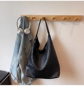 Detail of black woven leather tote bag showing intricate texture and large hobo shape