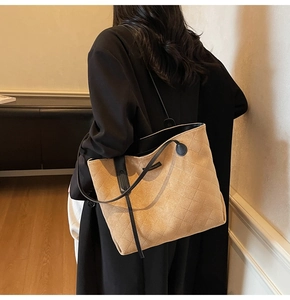 Detail of camel suede tote bag with diamond quilting and black shoulder straps on model