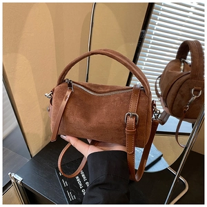 Detail einer braunen Wildleder-Zylindertasche mit Retro-Textur und Lederriemen