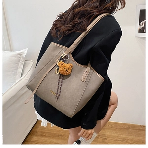 Detail of dark taupe tote bag in lychee texture leather with a cute bear charm