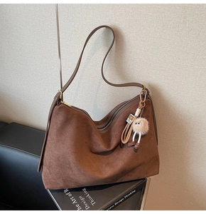 Vue détaillée du sac hobo en daim marron avec zip doré et accessoire en peluche