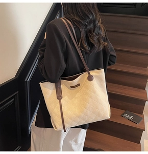 Detailed view of beige quilted tote bag with brown leather straps on a casual model