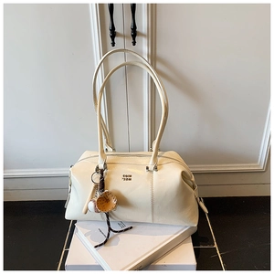 Detail of cream patent leather Boston bag featuring baseball themed charms and logo