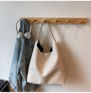 Detail of off-white woven leather tote bag with classic square texture and wide strap