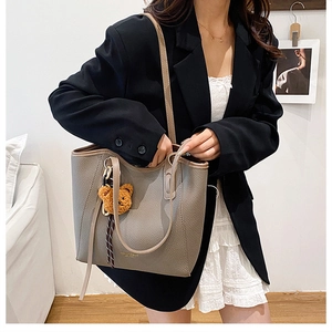 Close-up of grey pebbled leather tote bag with gold lettering and cute bear charm