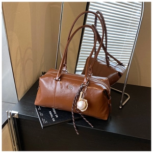 Close-up of brown vintage Boston bag featuring COIN 2DN print and baseball charm detail