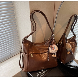 Detailed view of brown faux leather tote bag with plush lamb charm and metal zipper