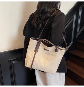 Detail of beige quilted faux suede tote bag with brown straps worn on the shoulder