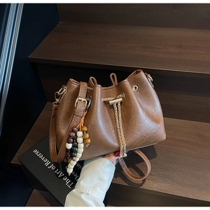 Detail of vintage brown drawstring bucket bag with gold chain and beaded ornament