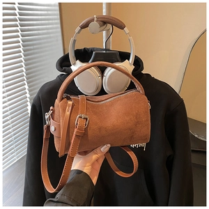 Detailansicht der braunen Zylindertasche aus Wildleder mit Silberschnallen und Gurt