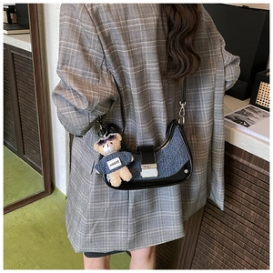 Detail of blue denim hobo bag with silver buckle and cute teddy bear charm on shoulder