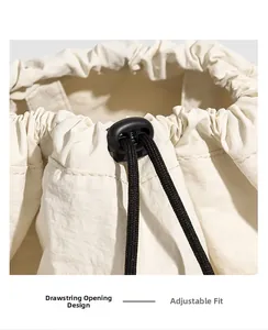 Detail of cream drawstring closure with black cord and spring toggle on nylon backpack